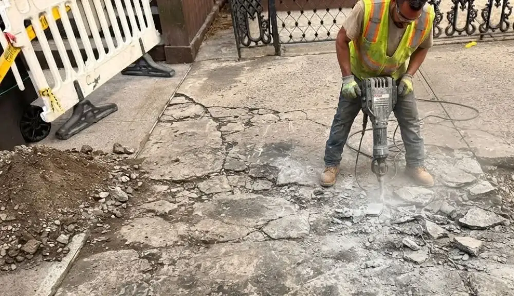 Damaged sidewalk concrete being removed for a DOT violation repair in Brooklyn