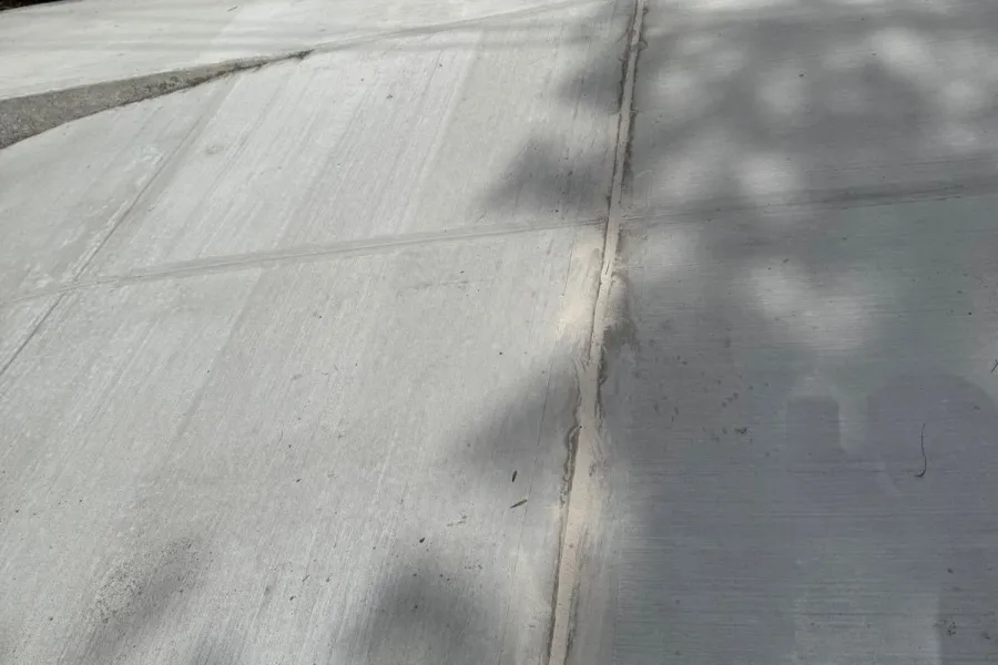 Repaired sidewalk and garage entrance at a two-family home in Flushing, Queens after NYC DOT violation removal.