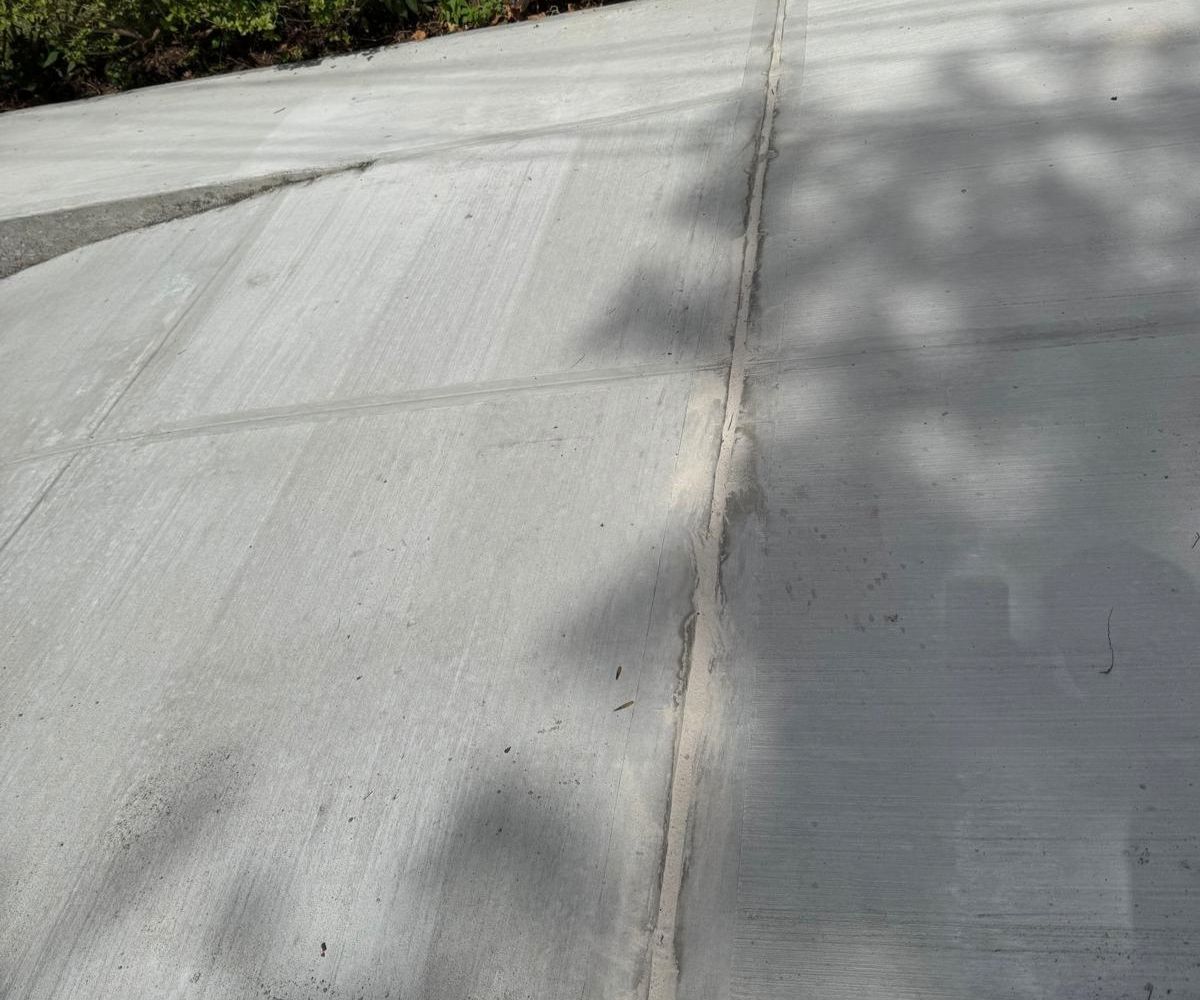 Repaired sidewalk and garage entrance at a two-family home in Flushing, Queens after NYC DOT violation removal.