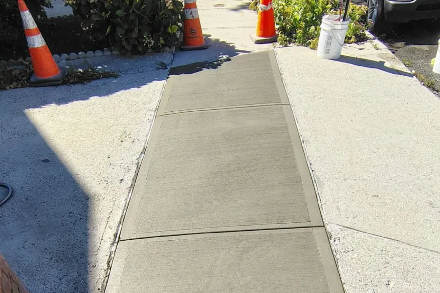 Three newly poured concrete sidewalk slabs with a broom finish and defined joints at 119-40 6th Avenue, College Point, Queens.