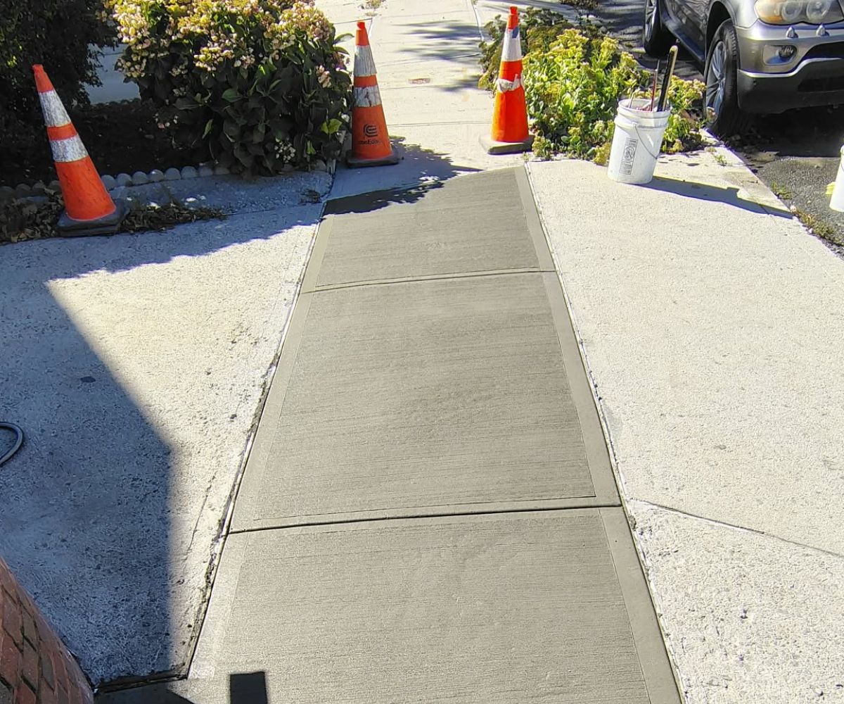 Three newly poured concrete sidewalk slabs with a broom finish and defined joints at 119-40 6th Avenue, College Point, Queens.