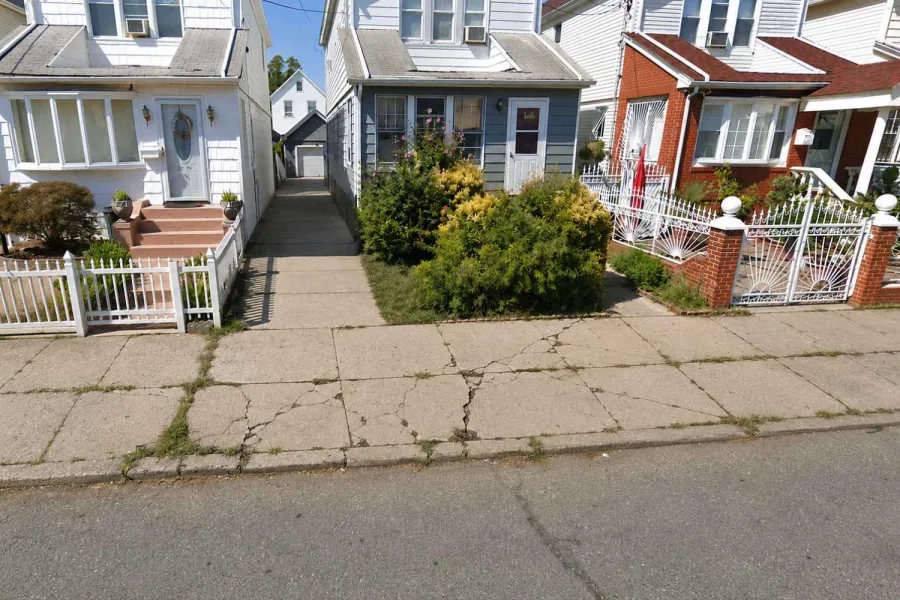 Cracked sidewalk before repair in Jamaica Hills, Queens