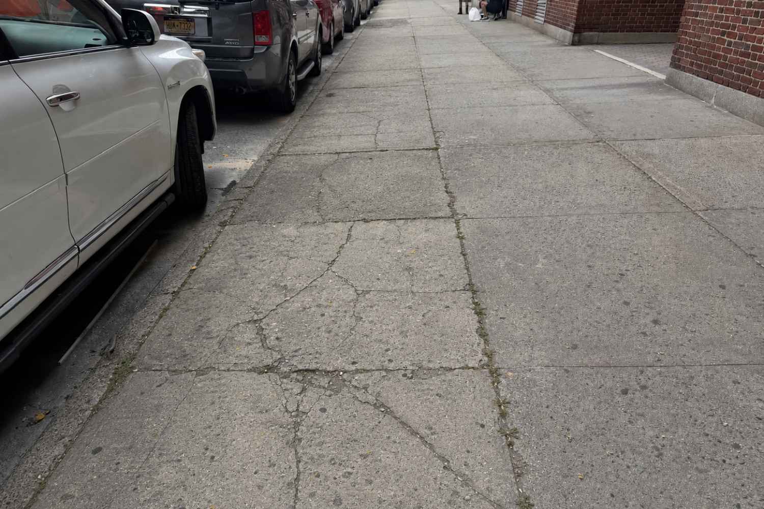 cracked and deteriorated concrete sidewalk before repair in sunnyside queens