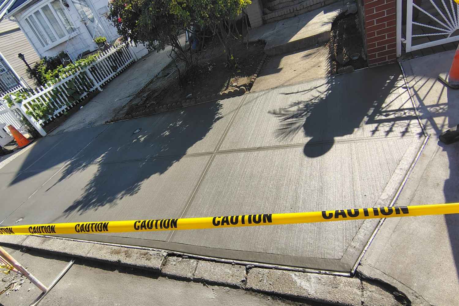 reshly replaced concrete sidewalk with safety tape at a Jamaica Hills property
